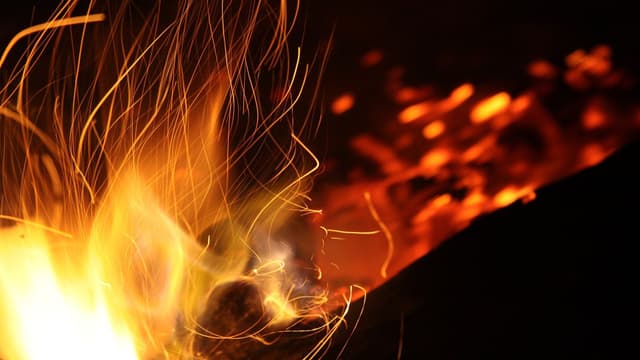 Liekki ja kipinät tummaa taustaa vasten