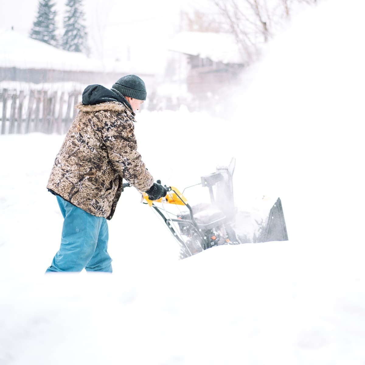 Mies auraa lunta pihassa lumilingolla