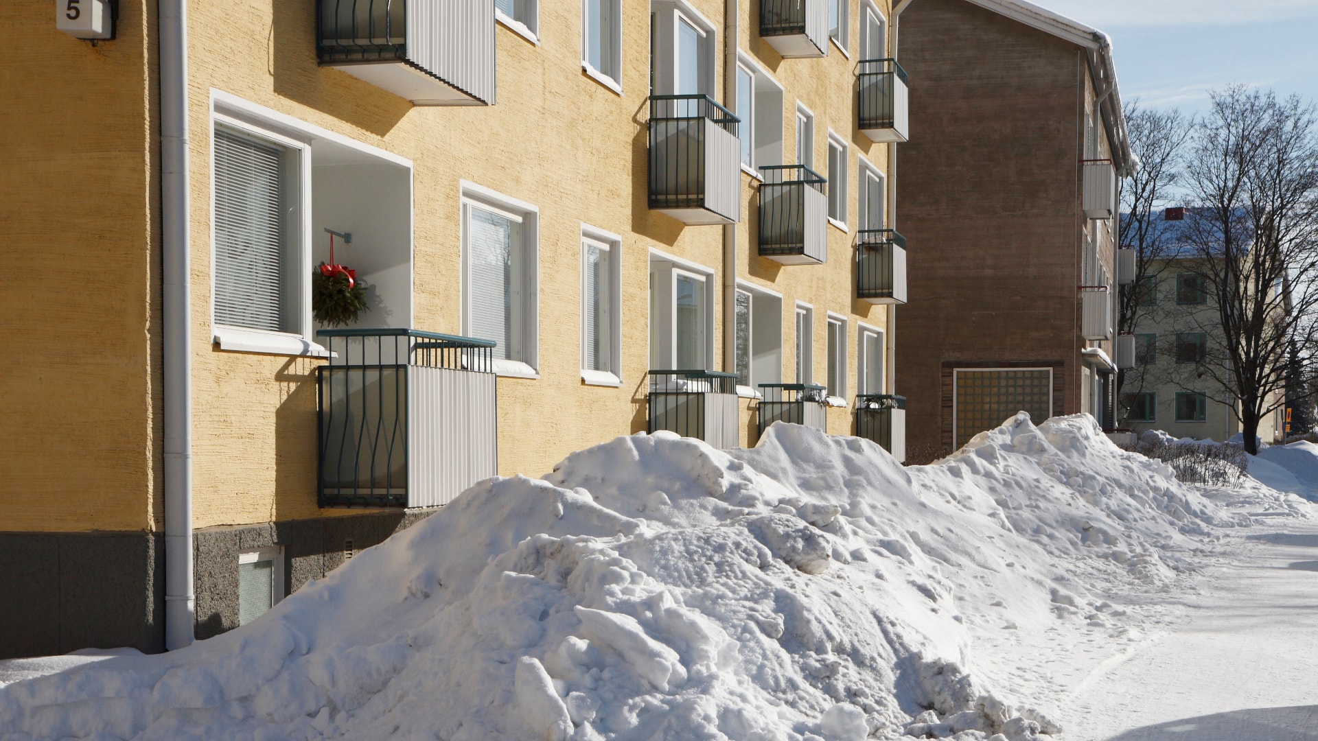 Vaaleita kerrostaloja lumisessa maisemassa auringon paisteessa