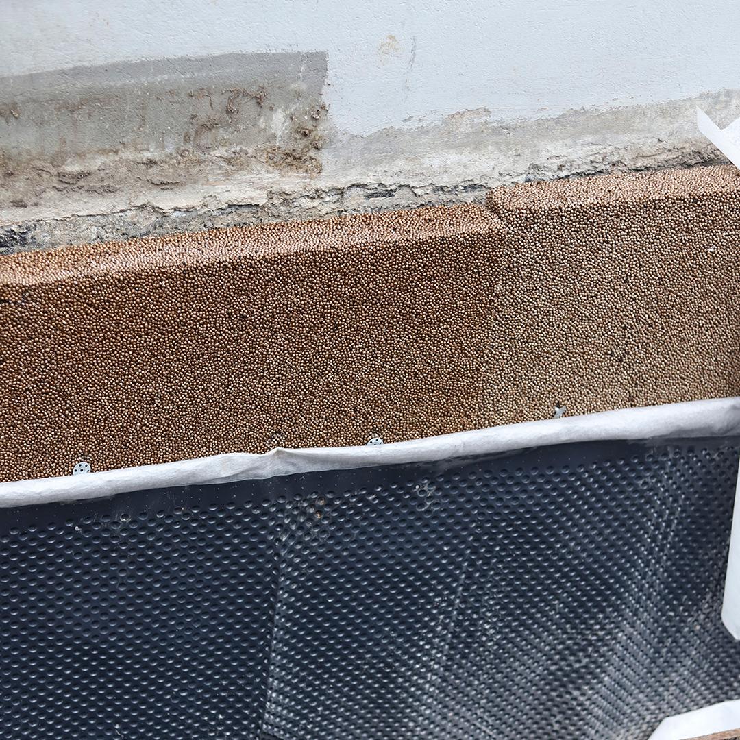 Isodrän-levy estää normien mukaisesti veden joutumisen rakenteisiin ja on sekä lämmöneriste että pystysalaoja muurin kyljessä.
