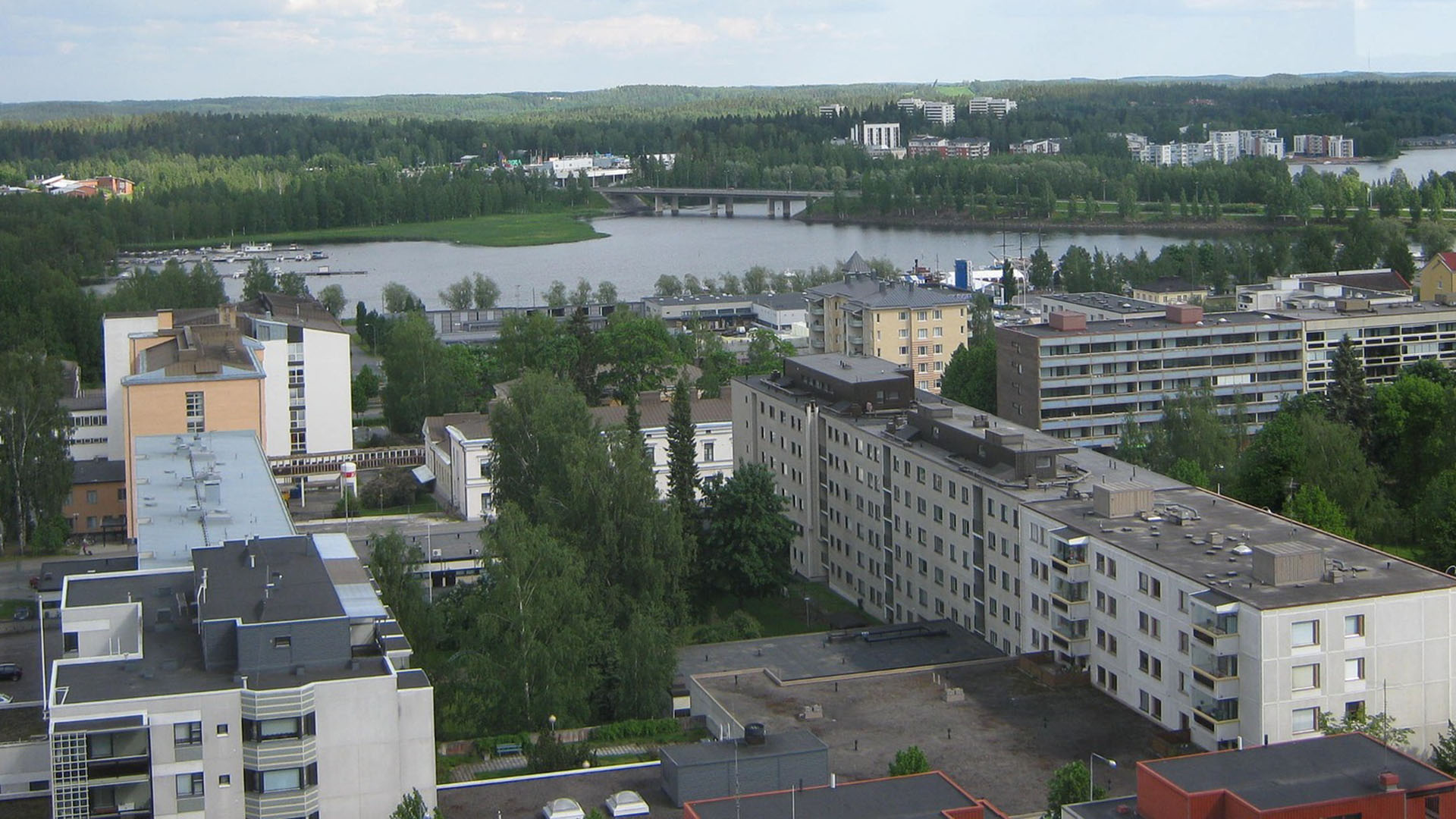 1920 kaupunkimaisemaa, jossa kerrostaloja sekä taustalla maisemaa ja vesistöä