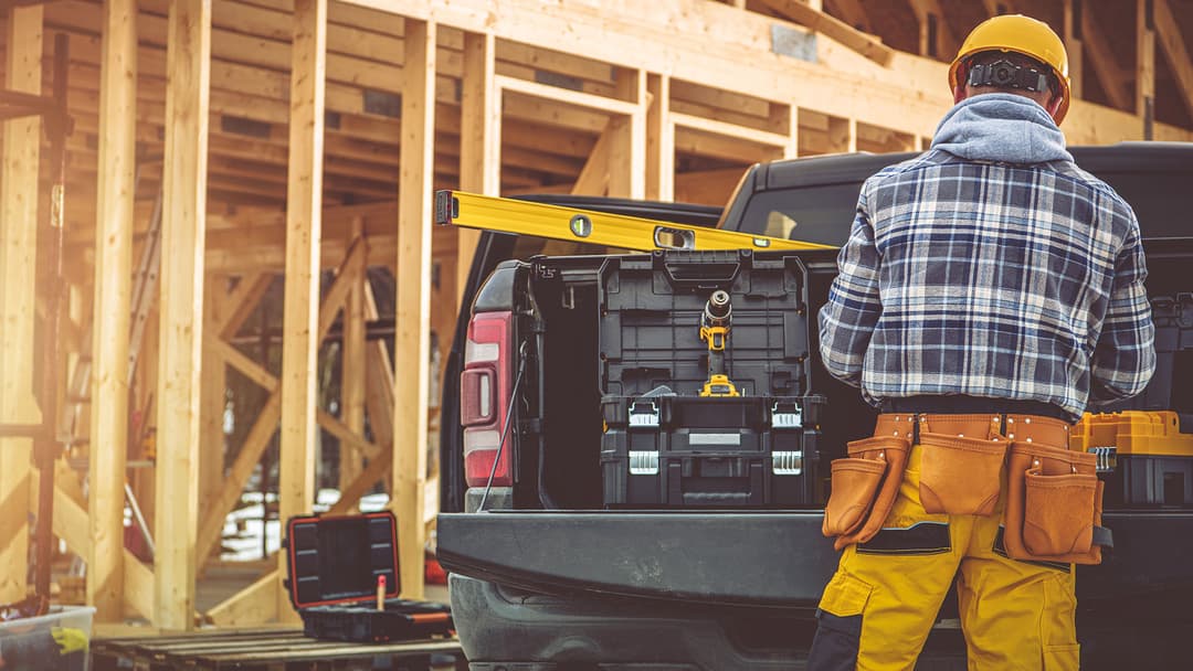 Kirvesmies työmaalla hakee tavaroitaan auton lavalta