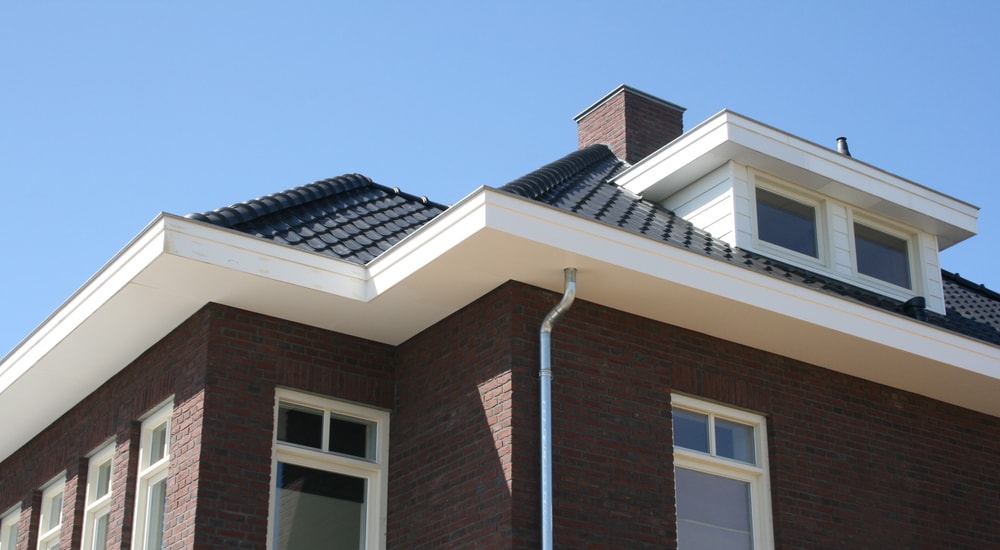 Tiilitalon kattoa sinistä taivasta vasten