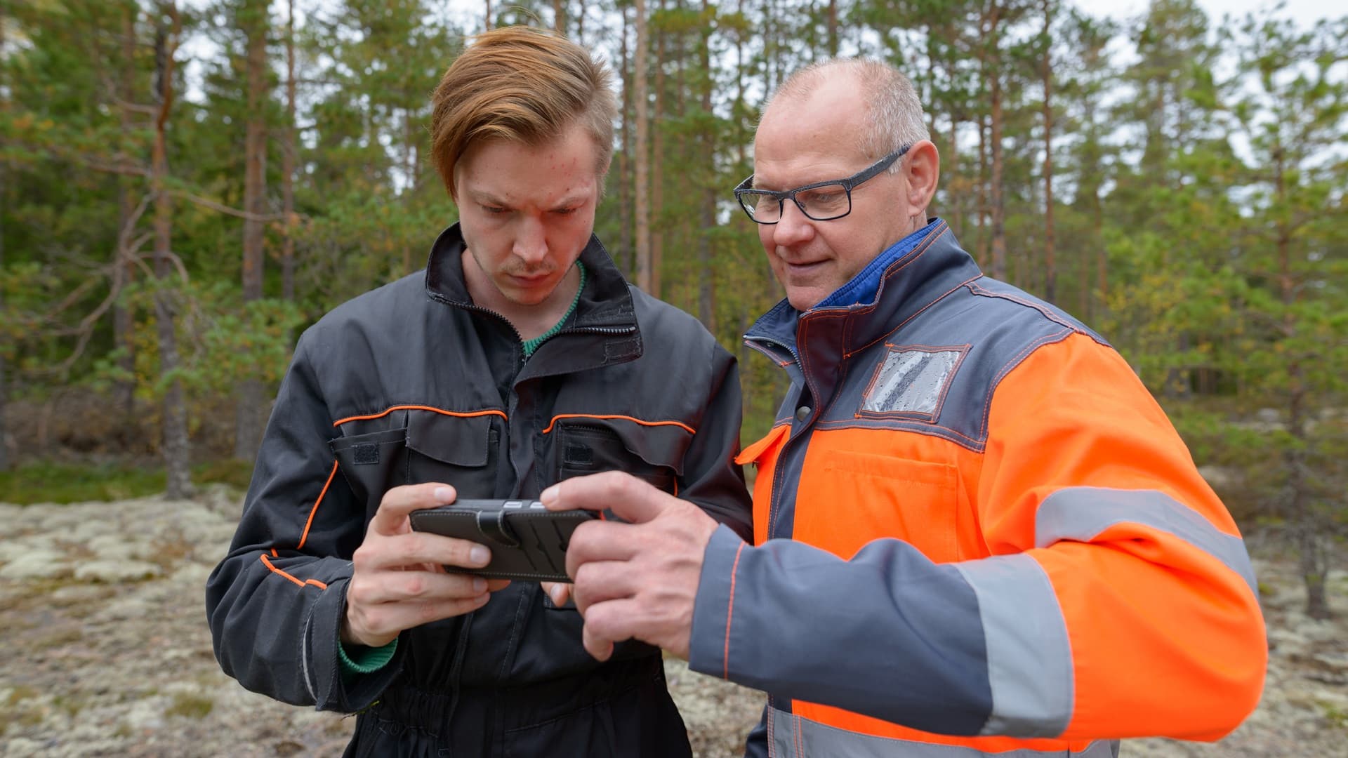 kaksi miestä katsoo puhelimesta jotain tarkkaan