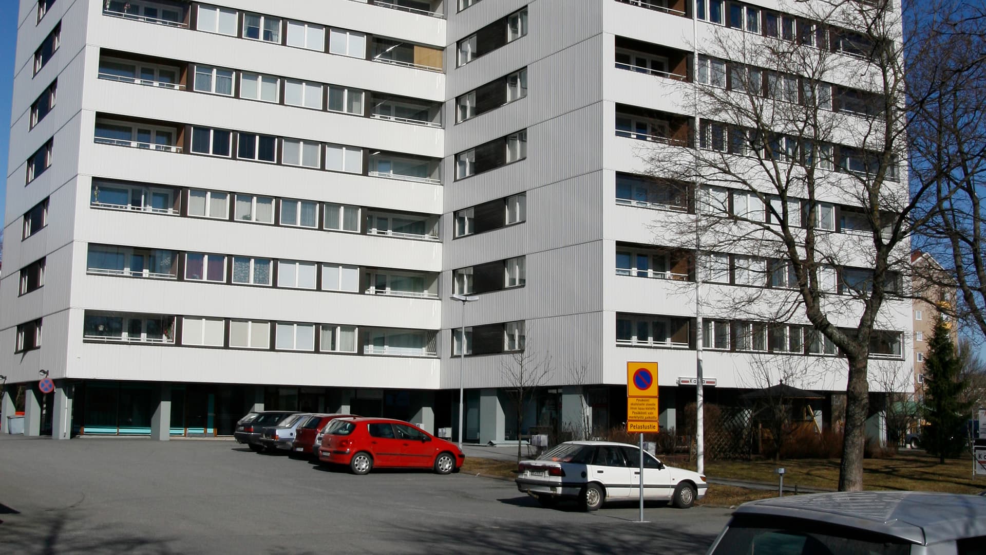 kerrostalon etupiha jossa autoja parkkeerattuna ja pysäköintikieltomerkki