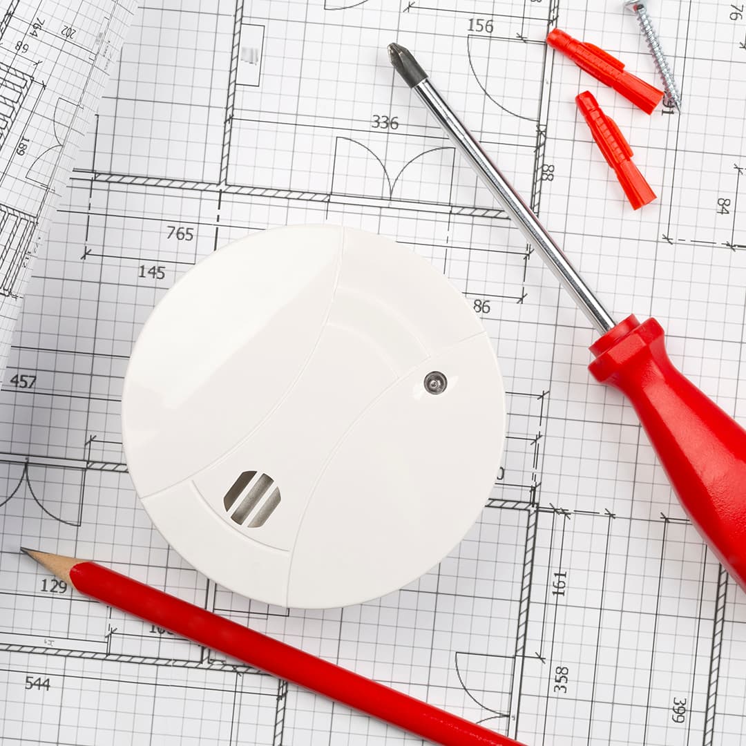 palovaroitin talon pohjapiirustuksen päällä ja samassa kuvassa lyijykynä sekä ruuvimeisseli