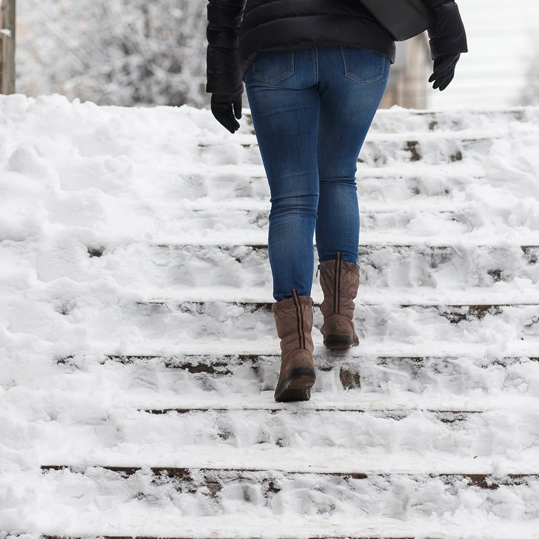 nainen kulkee hyvin lumisia ja liukkaita kivirappuja ulkona talvella
